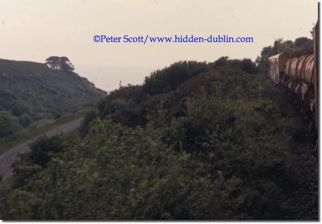 With the R675 road visible, and the Irish Sea also, engine 159 gentle leads the weedsprayer towards Ballinacourty, copyright Peter Scott